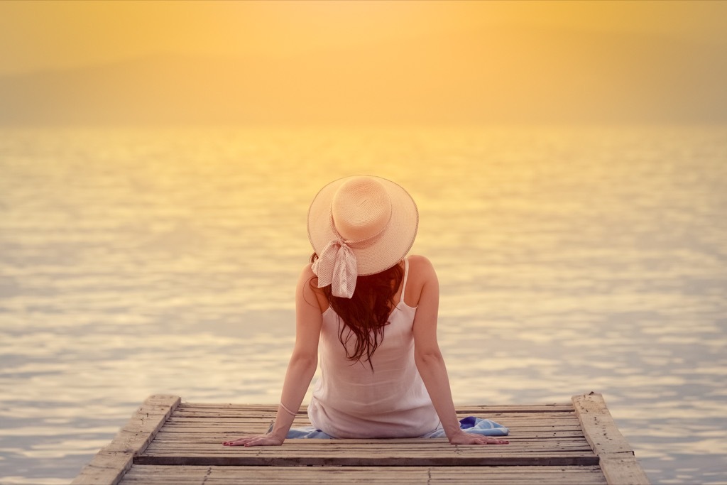 woman sitting on a dock at sunset