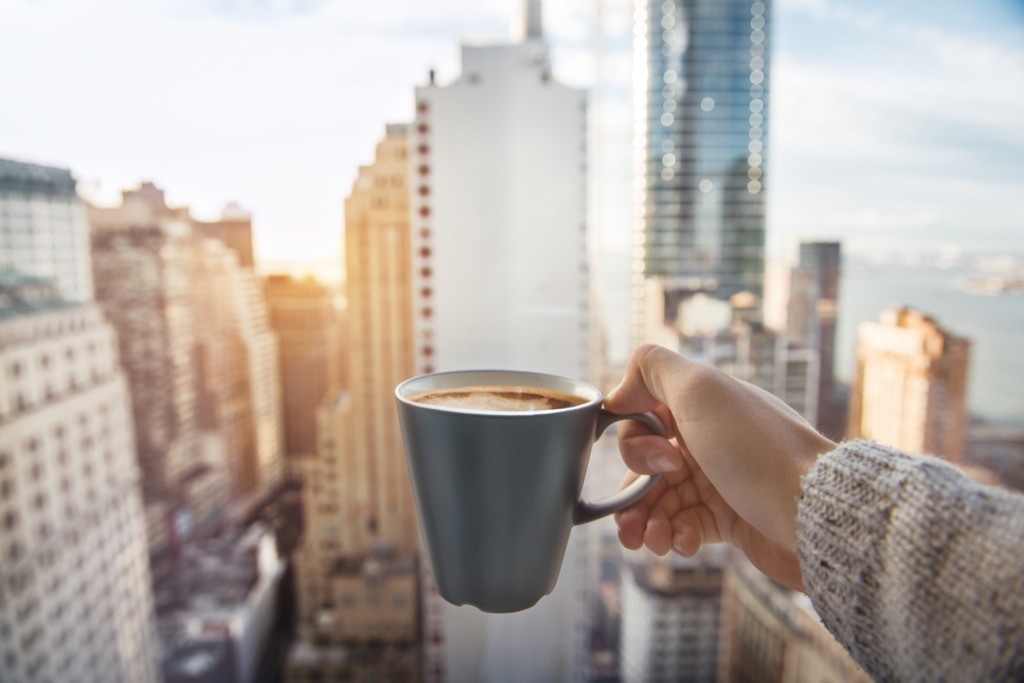 a cup of coffee in front of the manhattan new york skyline