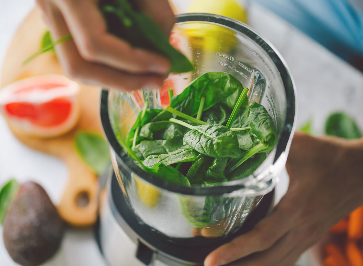 Putting spinach in blender for smoothie