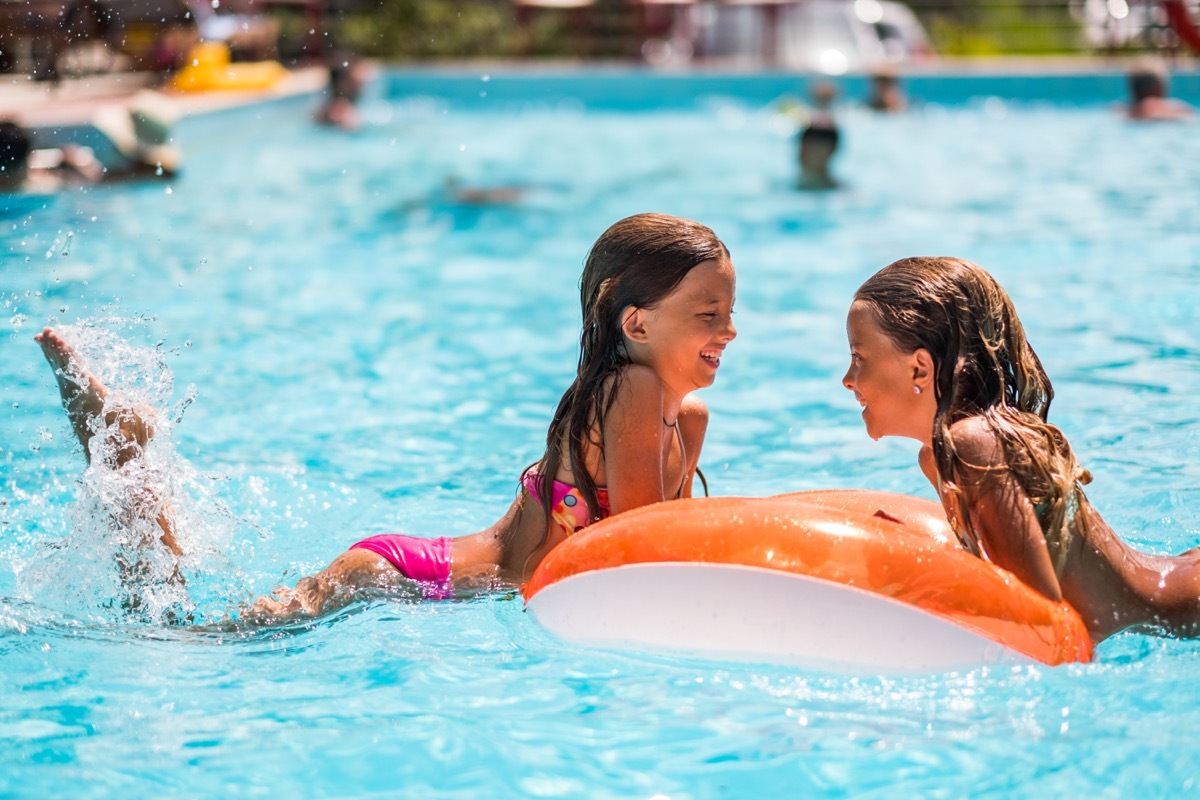 Two beauty girls floating in the pool and splashing