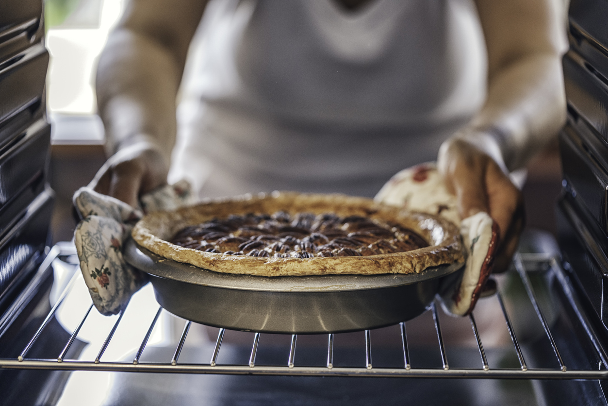 Person taking pecan pie out of the oven. 