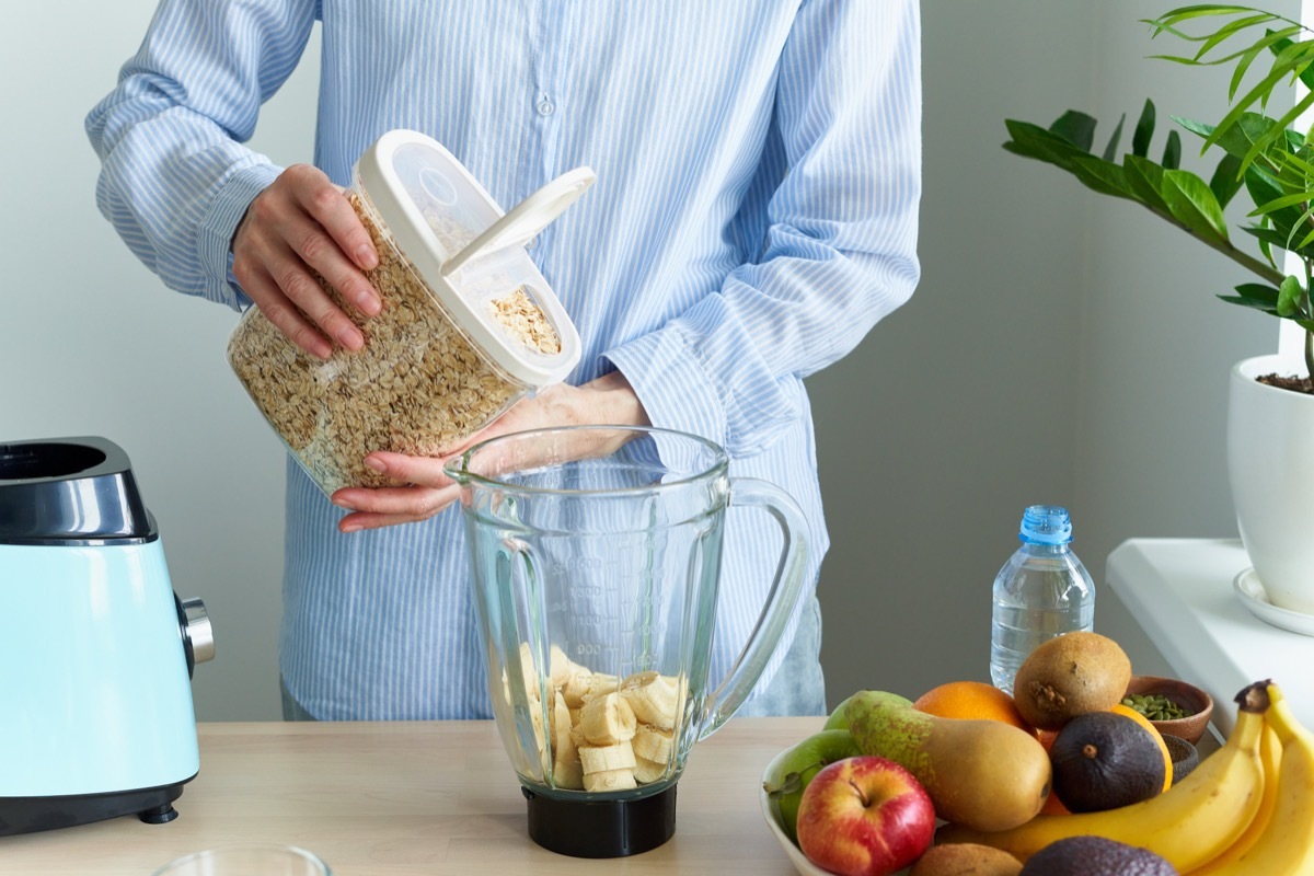 man pouring oatmeal into blender