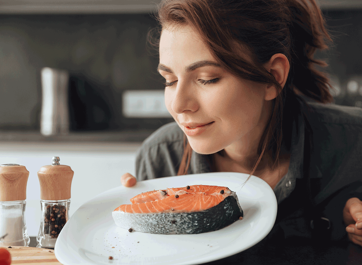 woman smelling piece of salmon