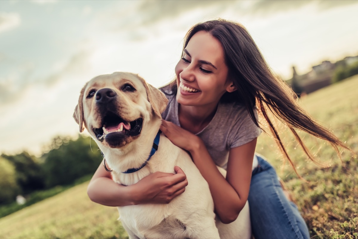 attractive young woman with labrador outdoors. Woman on a green grass with dog labrador retriever.