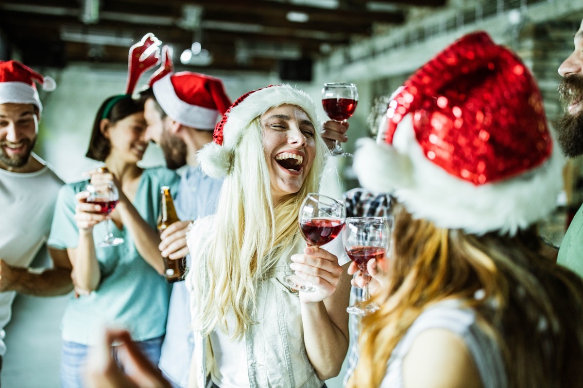 Group of cheerful creative people having fun on Christmas party in the office. Focus is on blond woman.