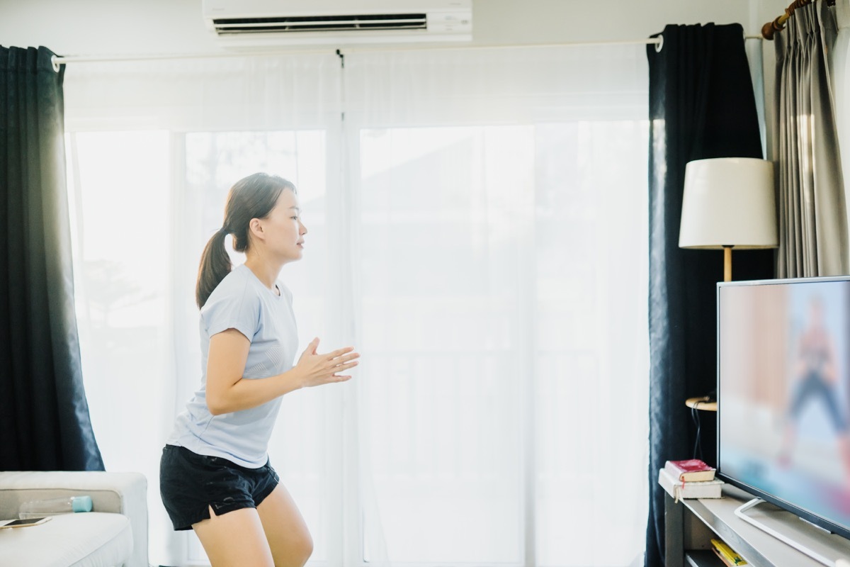 Woman doing at home dance lesson on tv in living room