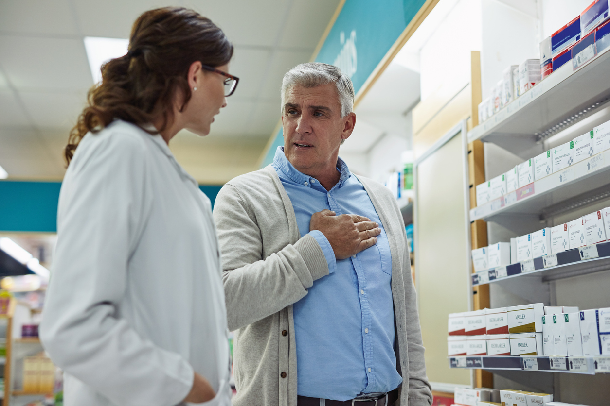 Pharmacist talking to a man suffering from pain in his chest.