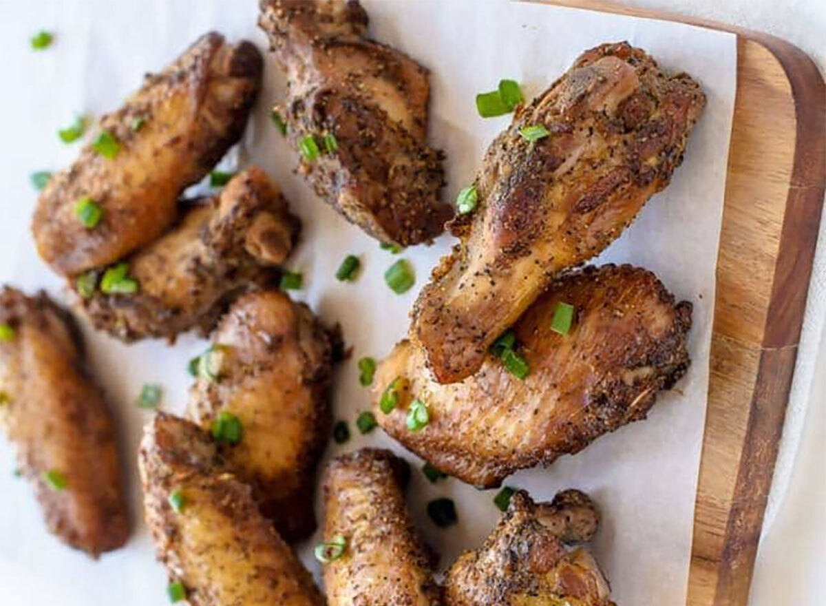 chicken wings made with black pepper and garlic on serving tray topped with scallions