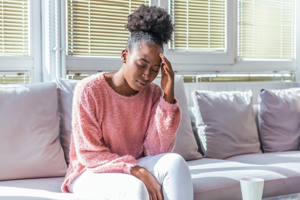 Woman sitting on couch with a headache