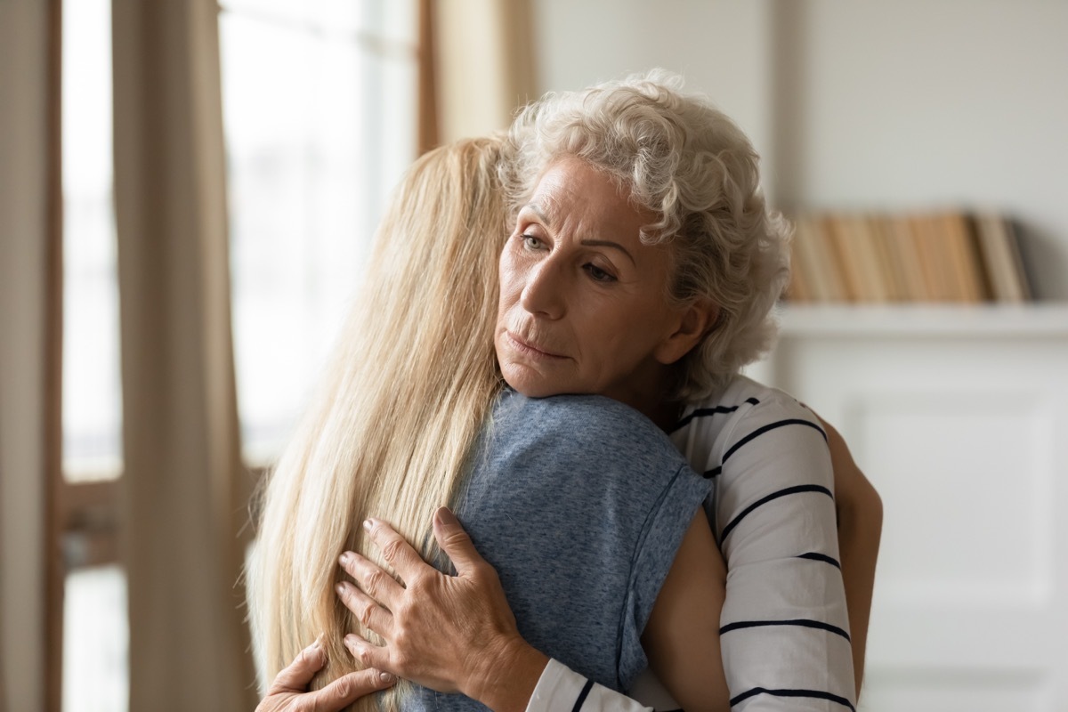 Young empathic woman embracing soothing comforting frustrated older mature mother. Grownup daughter apologizing to offended middle aged mommy. Two female generations family overcoming grief together.