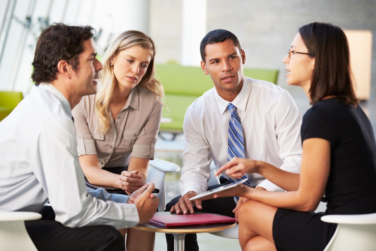 Businesspeople With Digital Tablet Having Meeting In Office