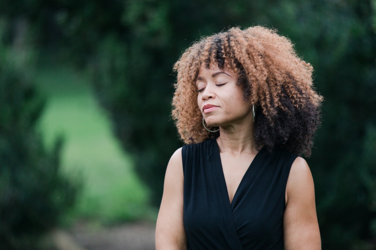 Middle Aged Woman Meditating Outdoors.