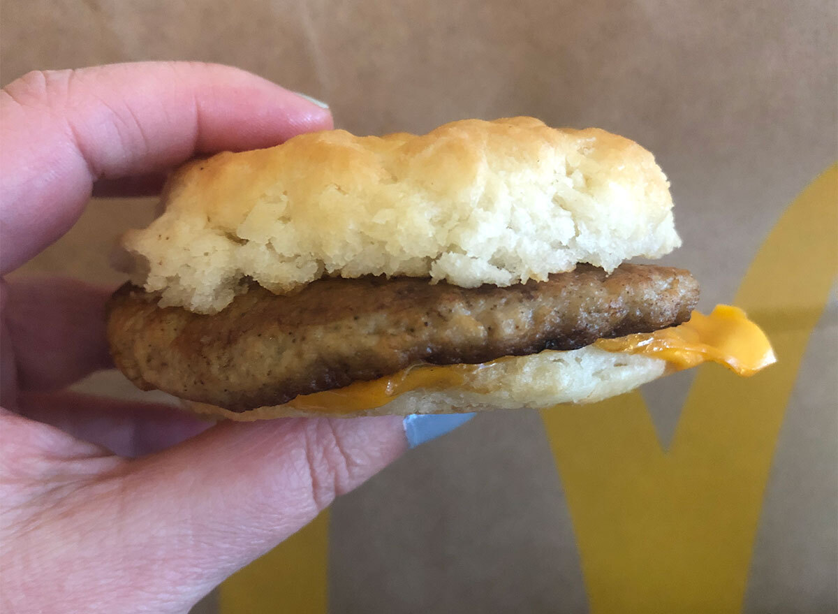 hand holding mcdonalds sausage and cheese biscuit