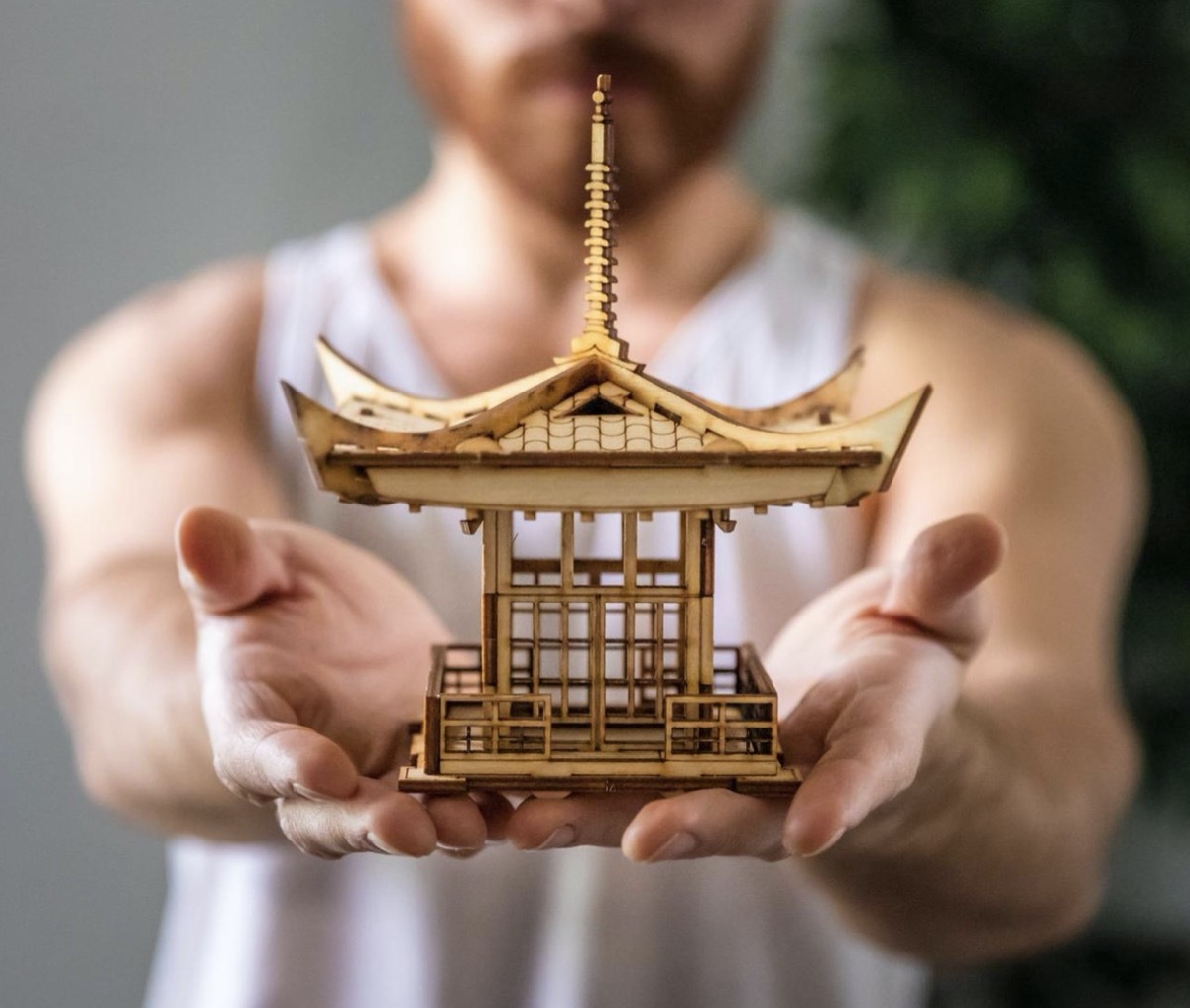 man holding tiny wooden pagoda