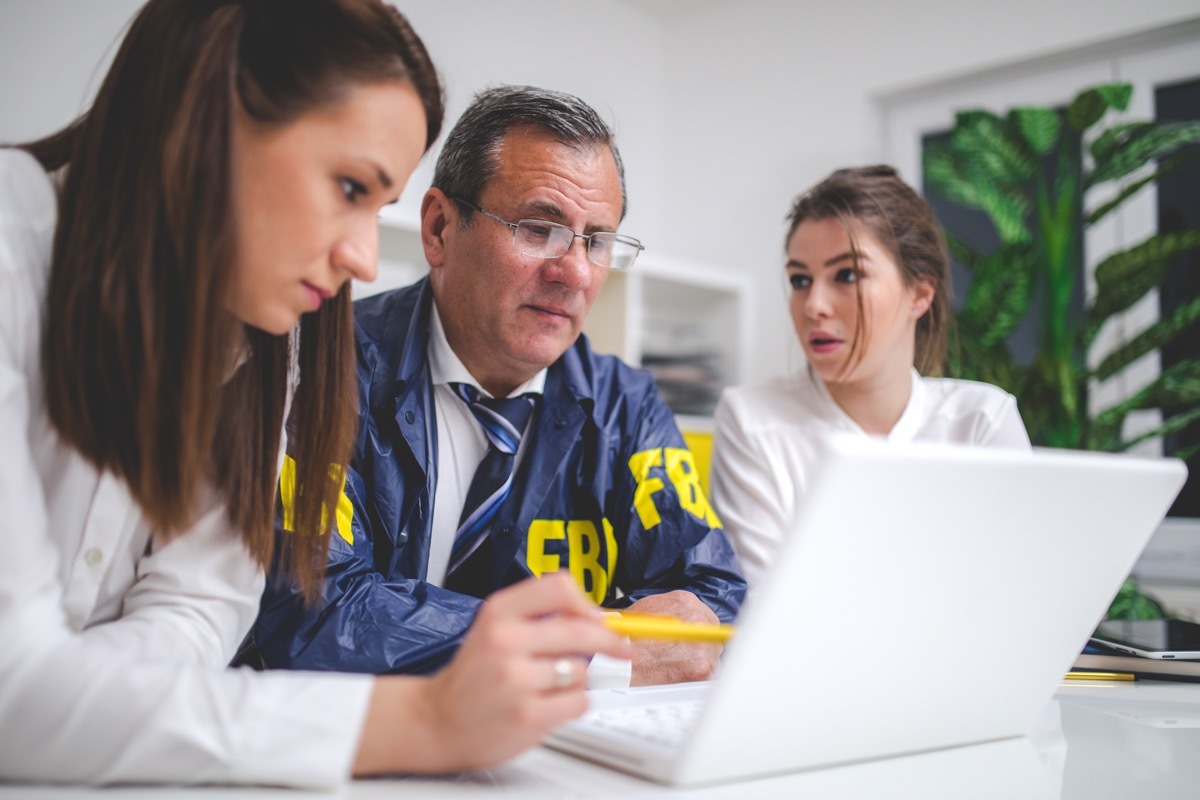 Successful FBI people working together in office on computer like a team.