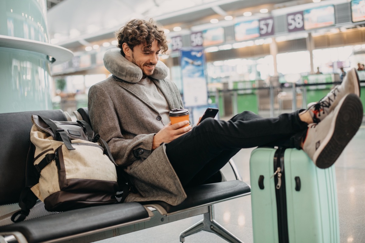 man with neck pillow at airport