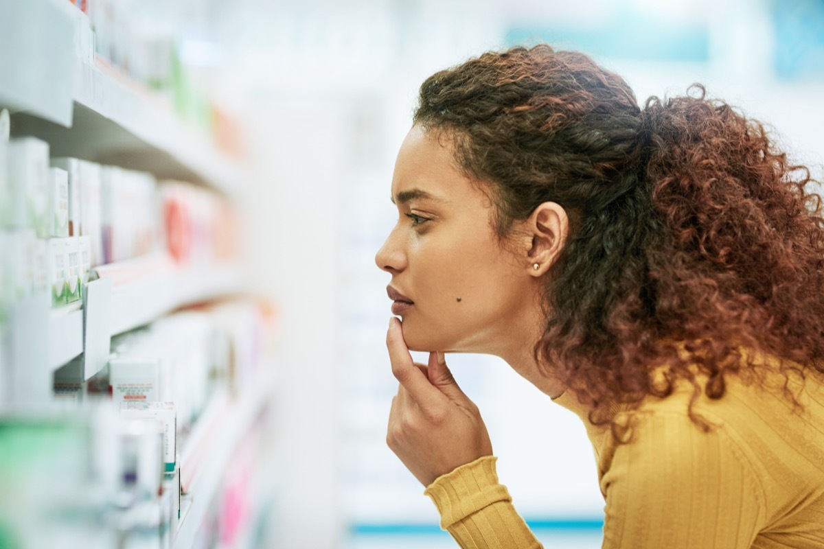 Shot of a young woman browsing the shelves of a pharmacy