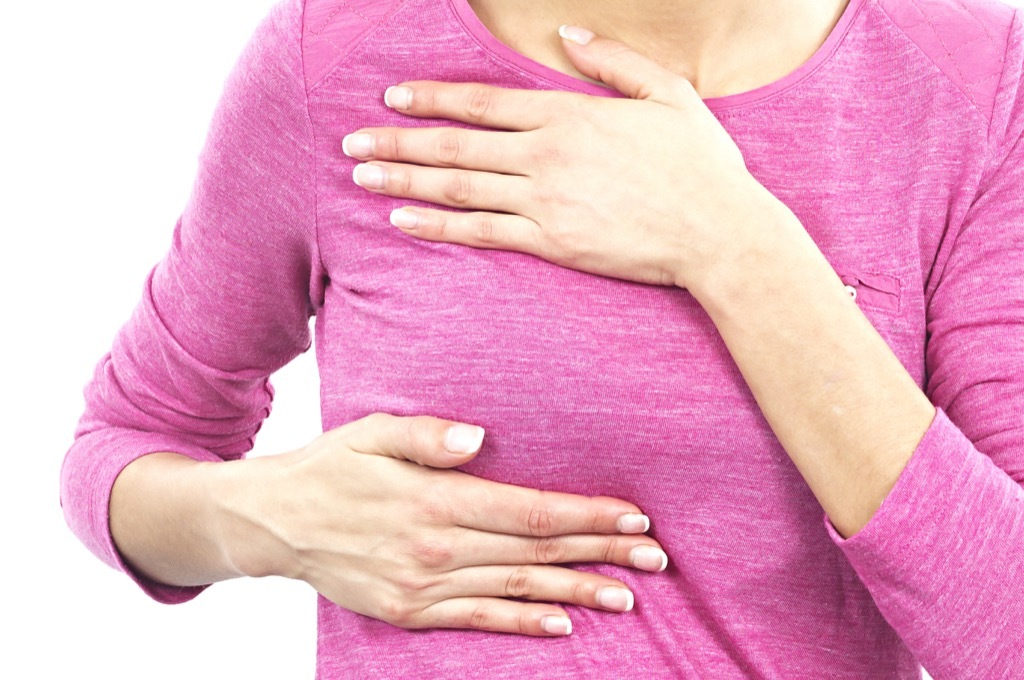 woman checking breast, subtle symptoms of serious disease