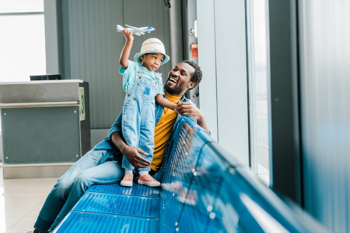 Father and son with airplane toy playing at airport gate