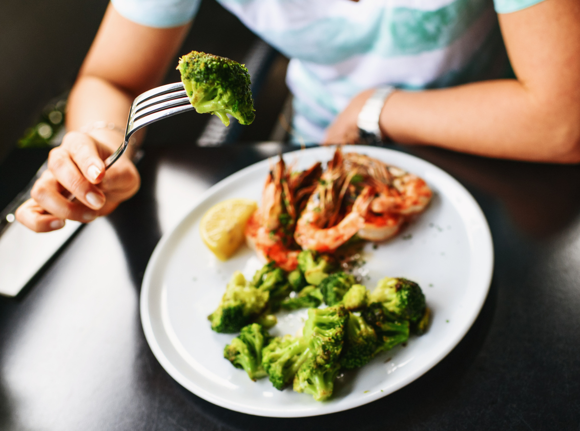 Person eating grilled broccoli.