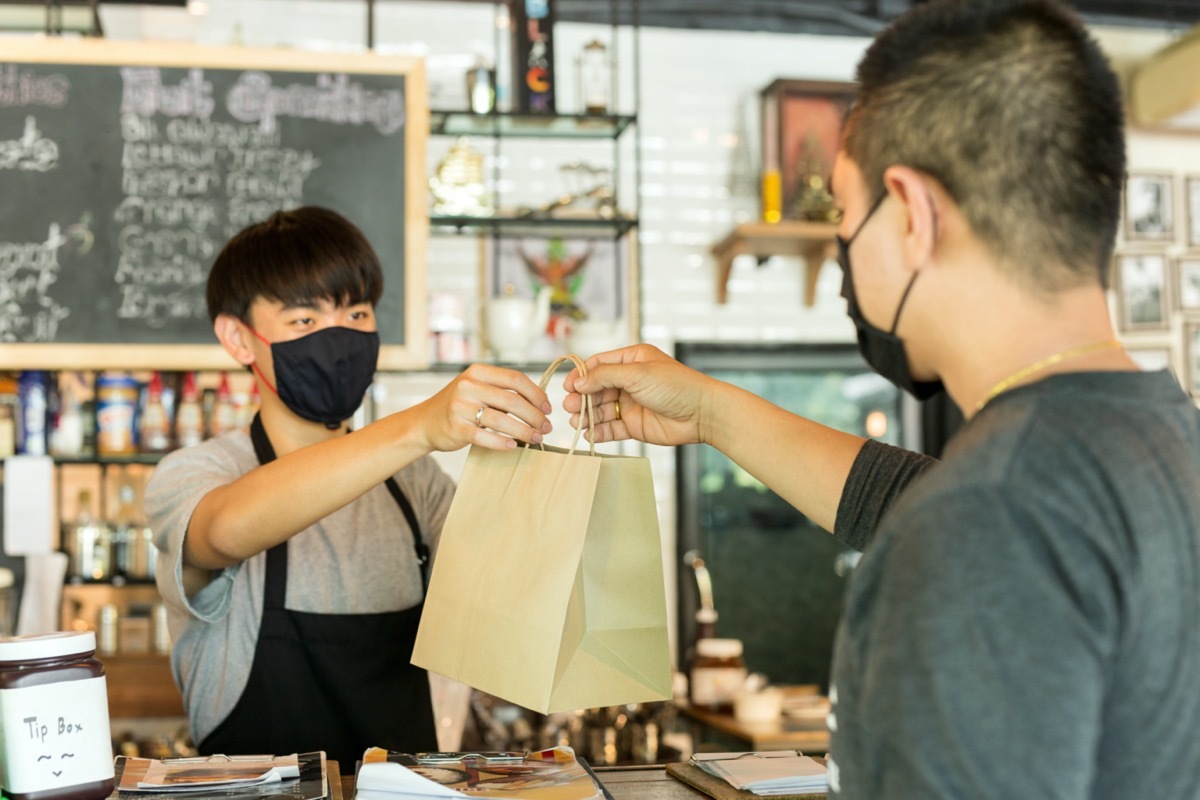 young asian man wearing coronavirus mask and getting takeout