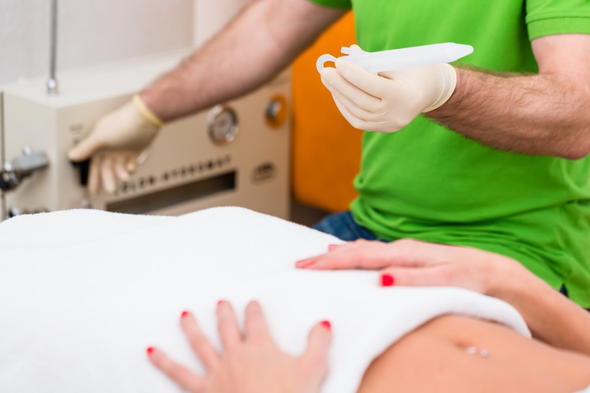 Woman at colon therapy with alternative practitioner lying on bench in practice