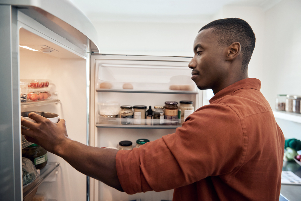 A young man taking items out of his fridge