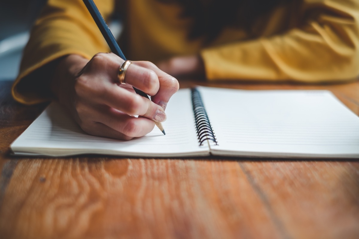 woman writing on a notepad with a pencil