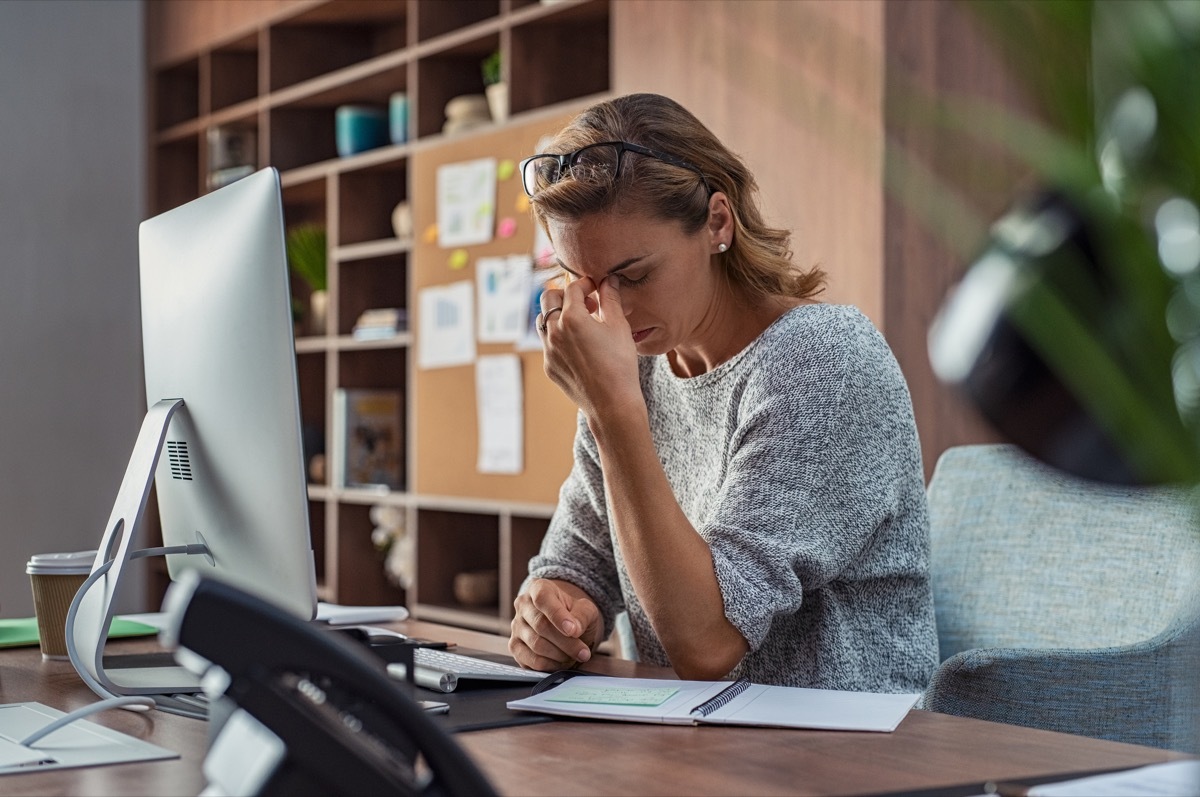 woman sitting at a desk with eye pain