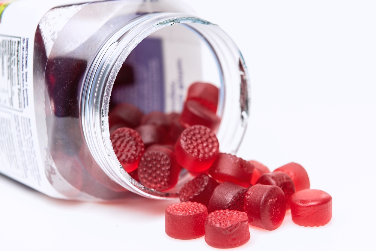 Vitamin supplements in gummy form spilling out of bottle. 