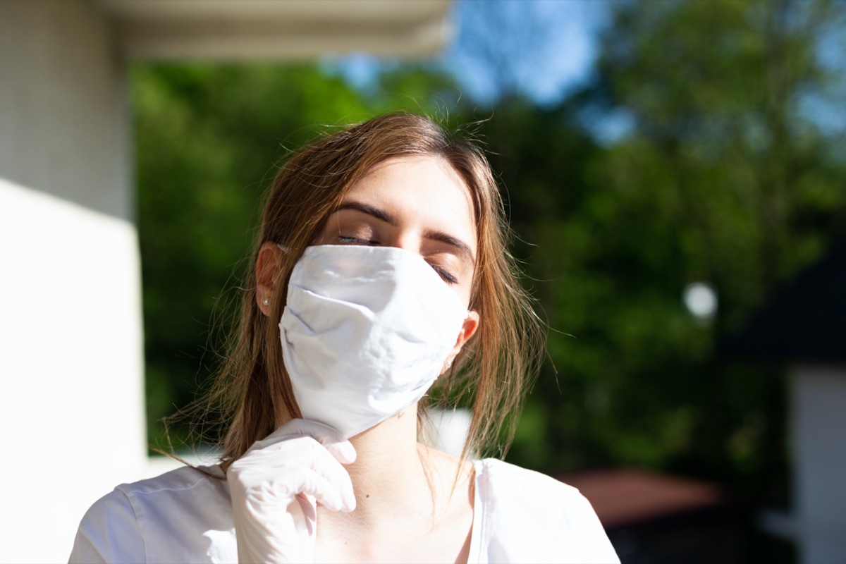 Woman wearing cotton white mask outdoors.