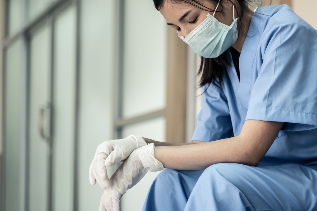 Medical team nurse feeling tired and sad from working to cure patients during covid 19 pandemic. Young woman take a break sitting close her eyes and rest after hard work at emergency case in hospital.