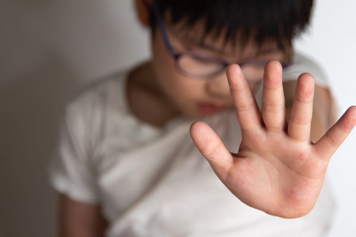 Asian boy puts up hand to stop from being spanked