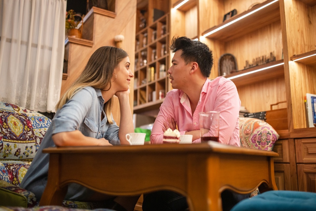 white woman gazing lovingly at asian man in den with cake