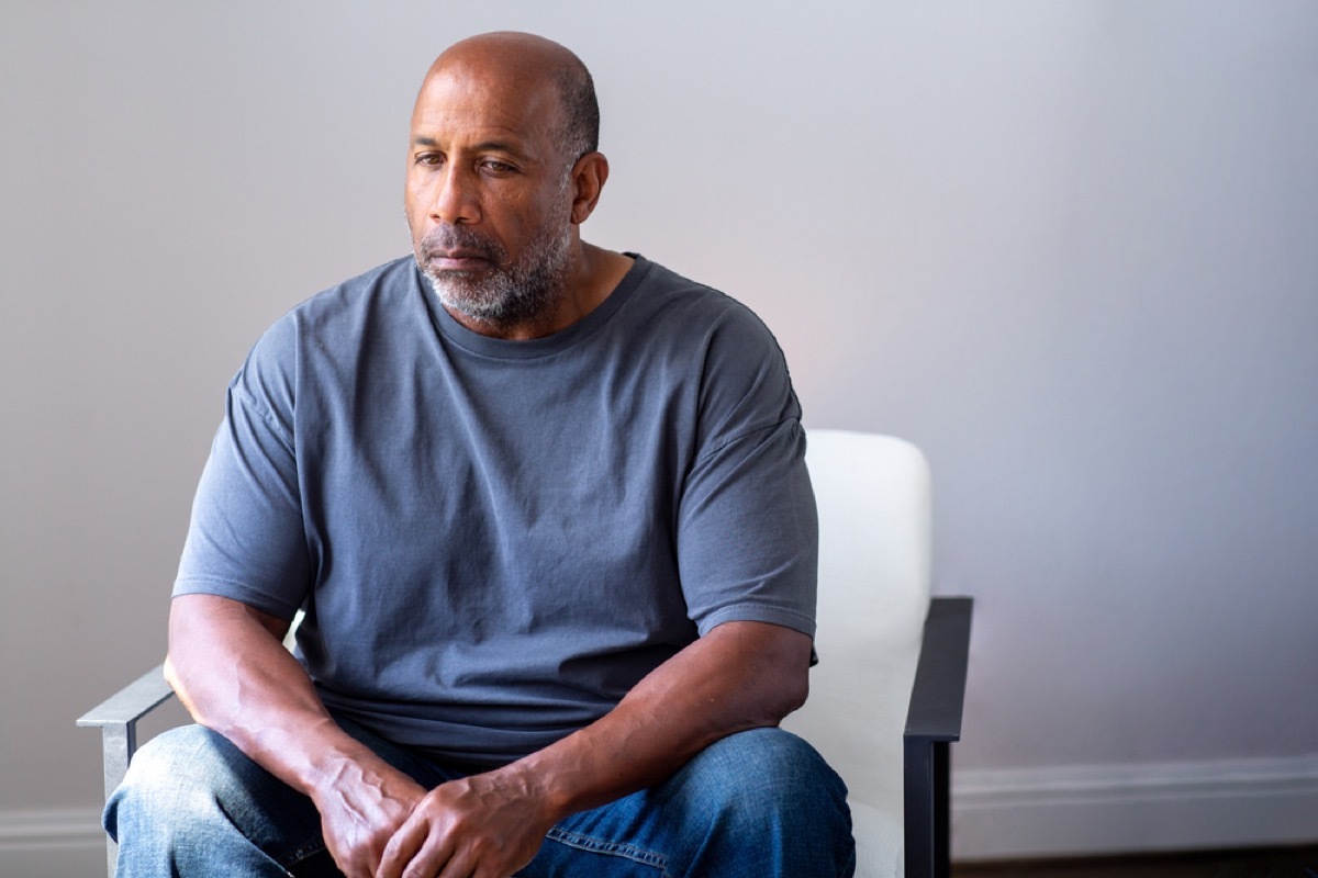 older man sitting on a chair and looking sad and confused