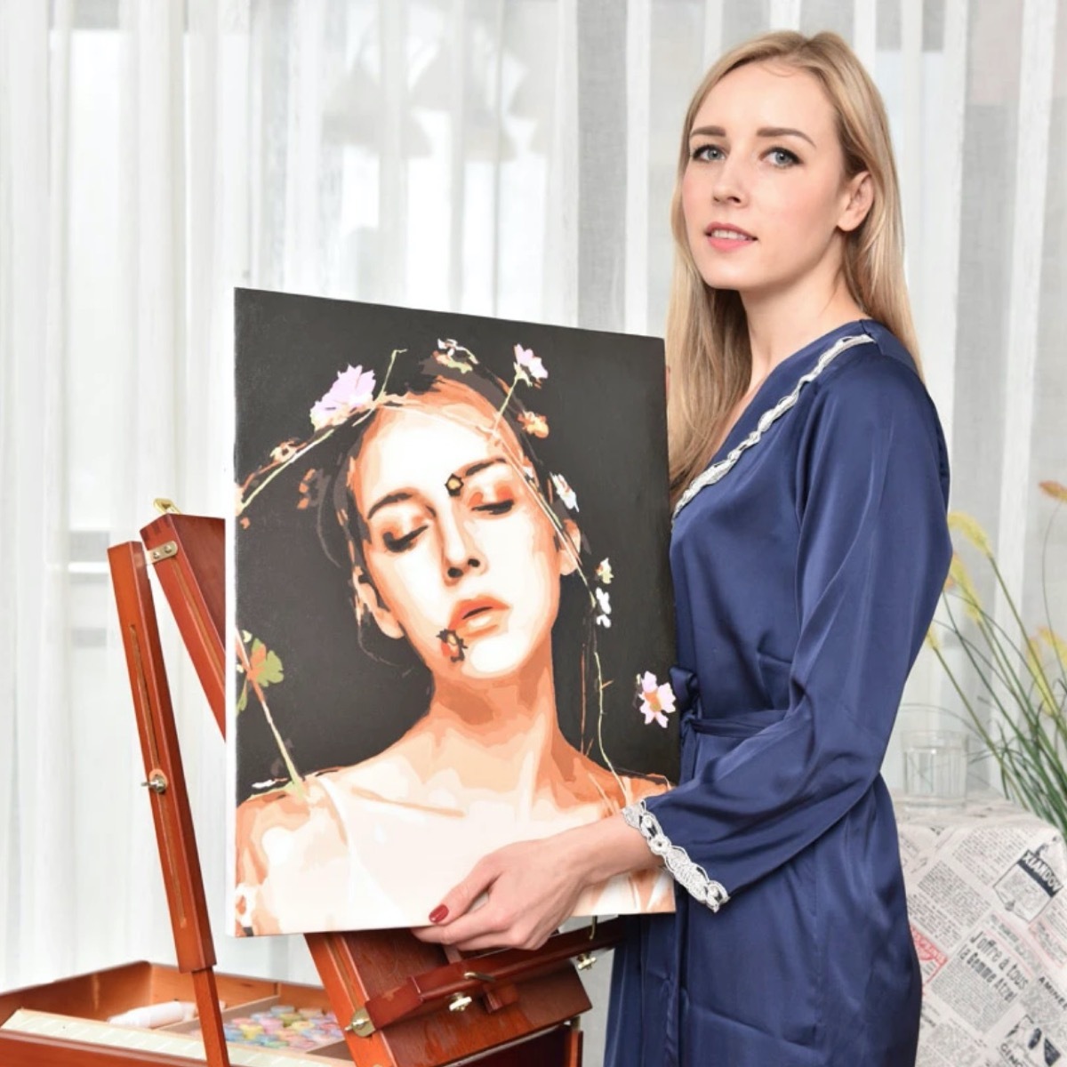 young blonde woman in blue robe holding painting of herself