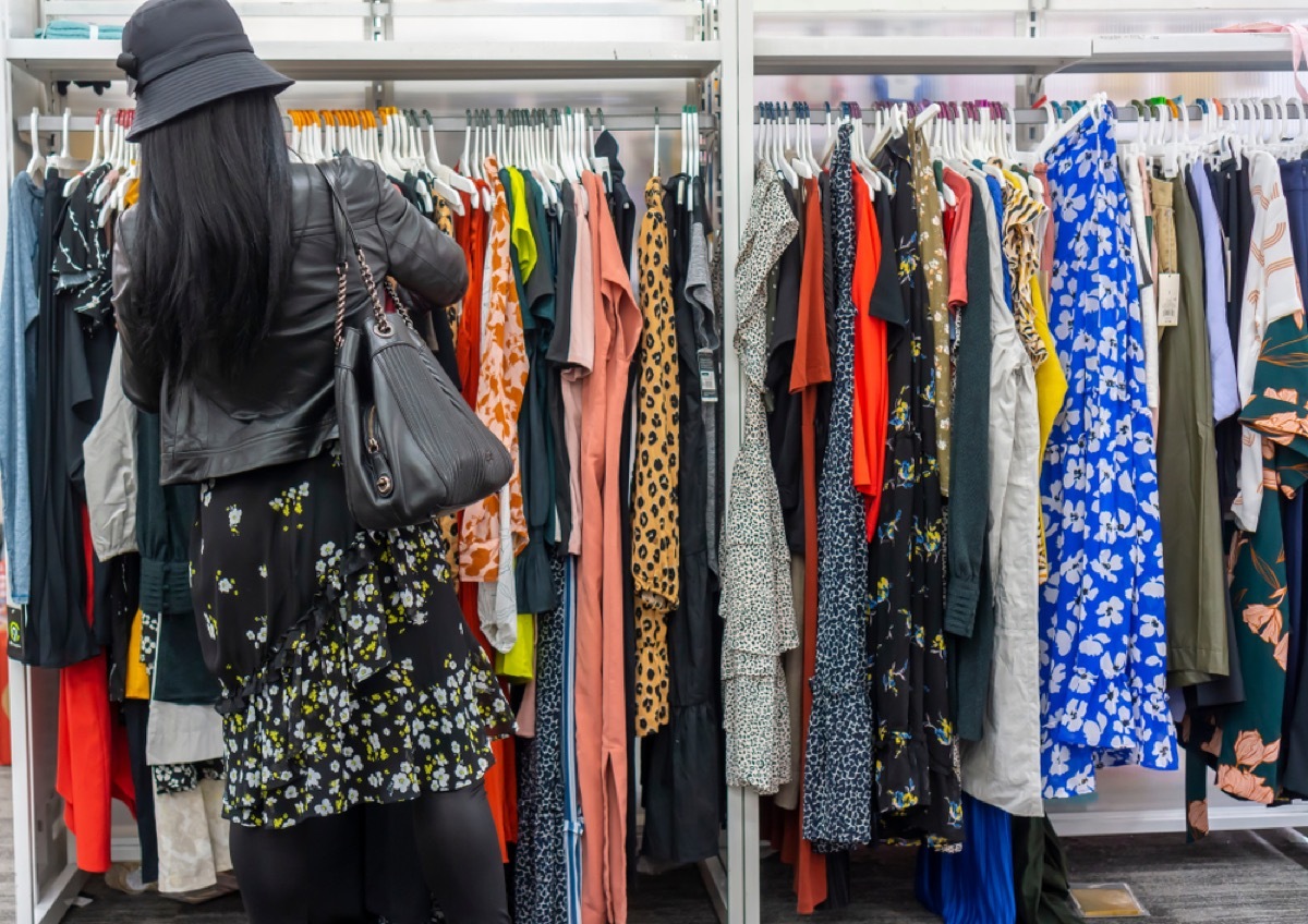 woman shops through rack of clothing