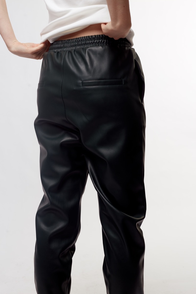 Woman wearing black leather elastic waist pants