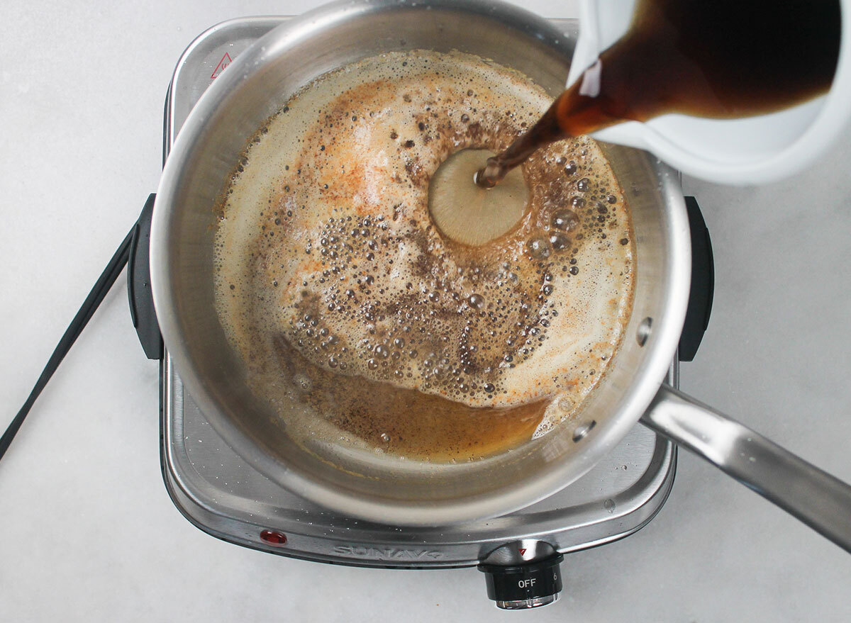 adding coca cola to a pot with butter for cake