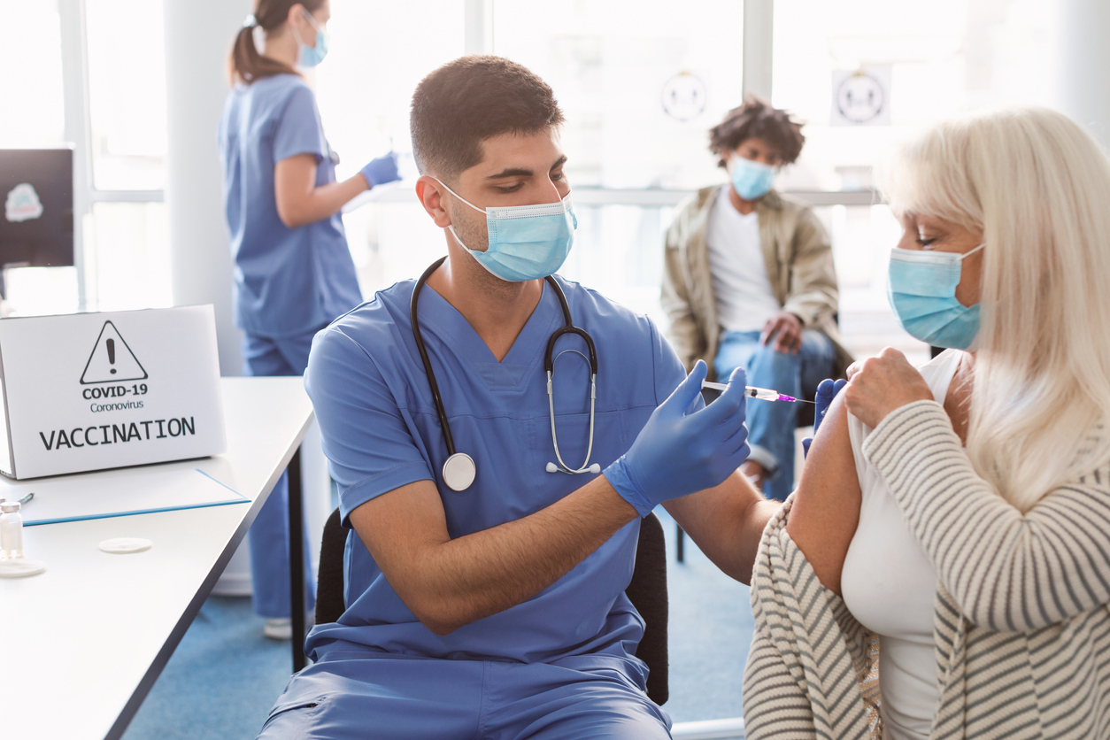 A senior woman receiving a COVID-19 vaccine or booster from a healthcare worker