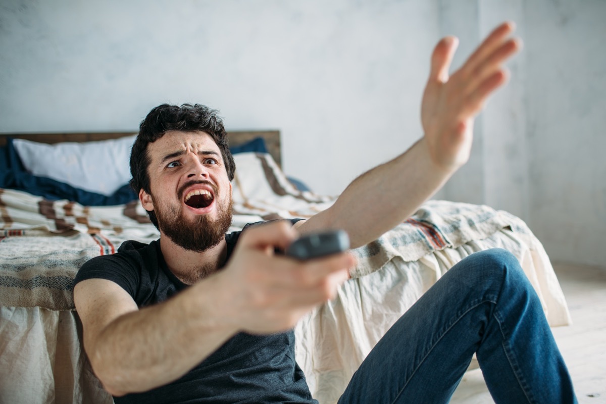 Man is angry while he is watching television on the floor