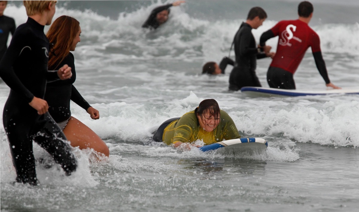 DEEP9N Sept. 15, 2013 - San Diego, California, United States - September 15, 2013_San Diego, California_USA_| Malina Gomez, 38, smiles as she catches a wave for the first time. Gomez, who is blind and has a prosthetic leg, says she is not particularly athletic but she likes swimming so wanted to try surfing. The annual surf camp for sight-impaired youth and adults was held Sunday morning at South Carlsbad (Ponto) Beach. Teams assisted people out into the surf and coached them through riding waves, some of whom had never seen the surf. The event is sponsored by the Swamis Surfing Association, the En