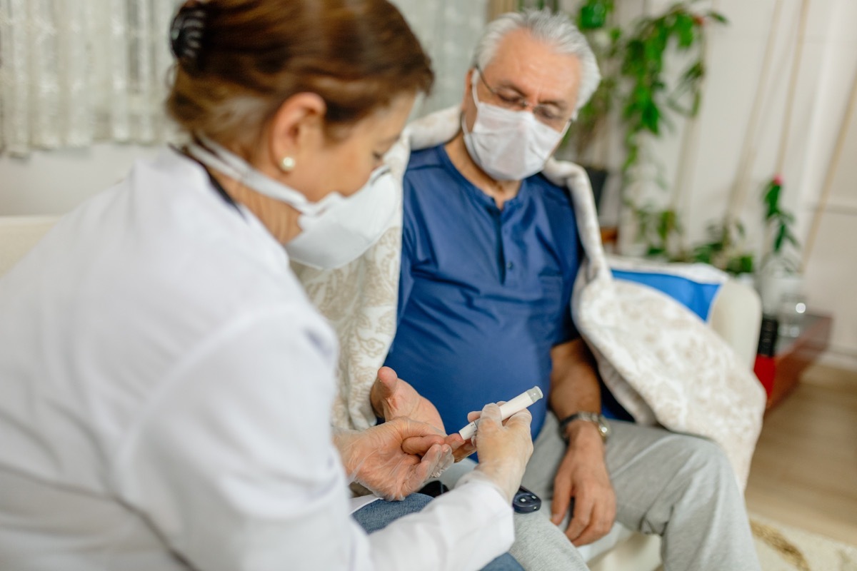 man gets blood sugar levels checked by nurse, both wear masks