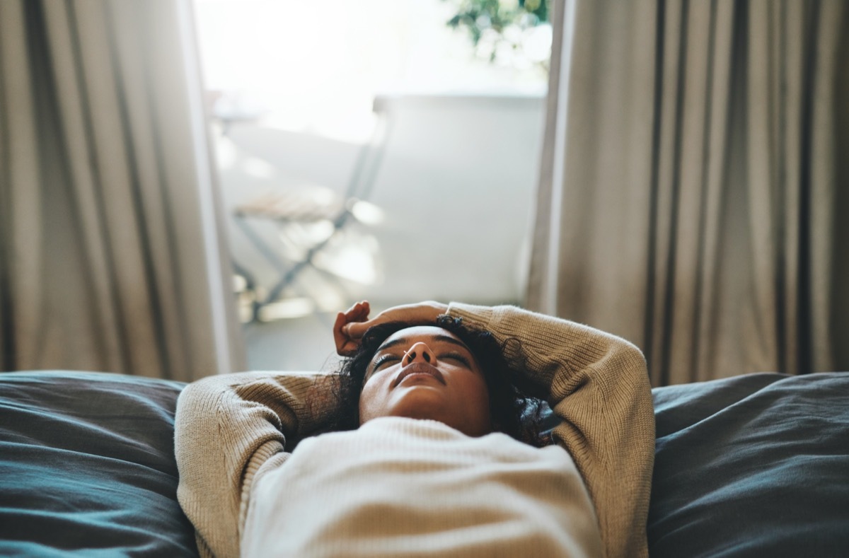 Woman lying on her bed with her eyes closed.