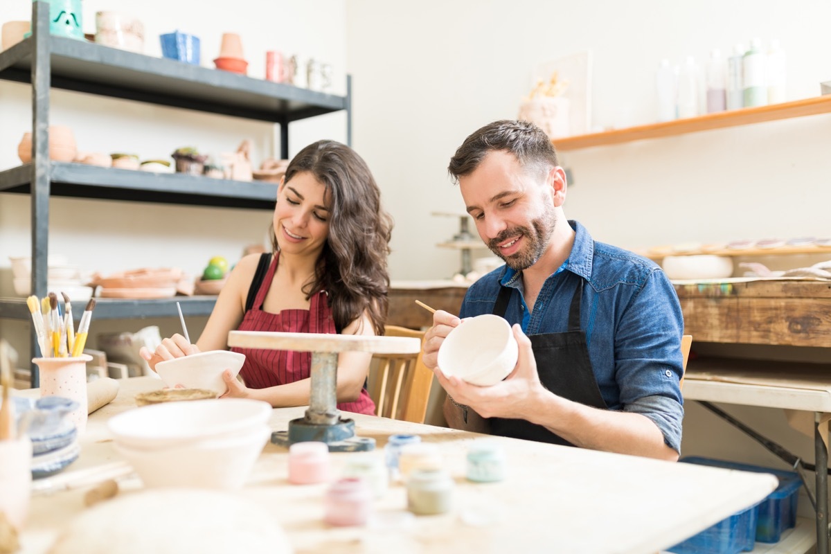 Couple taking an art class painting clay bowls