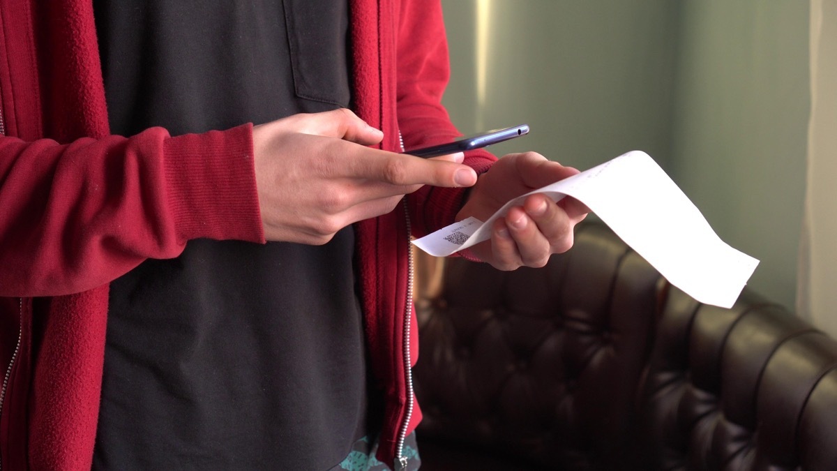 man in red sweatshirt scanning receipt