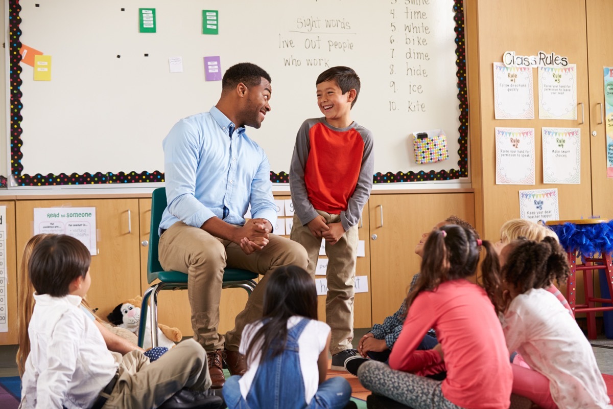 student talking to teacher as classmates listen in