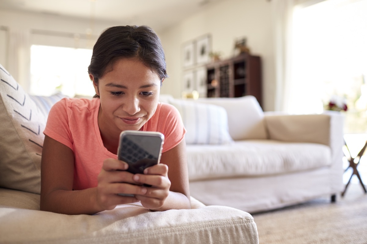 teenage girl lying on the sofa while on her phone