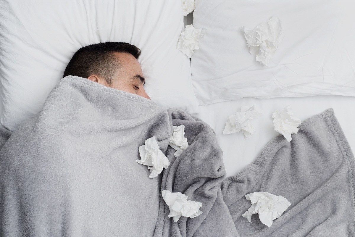 sick white man in bed with tissues