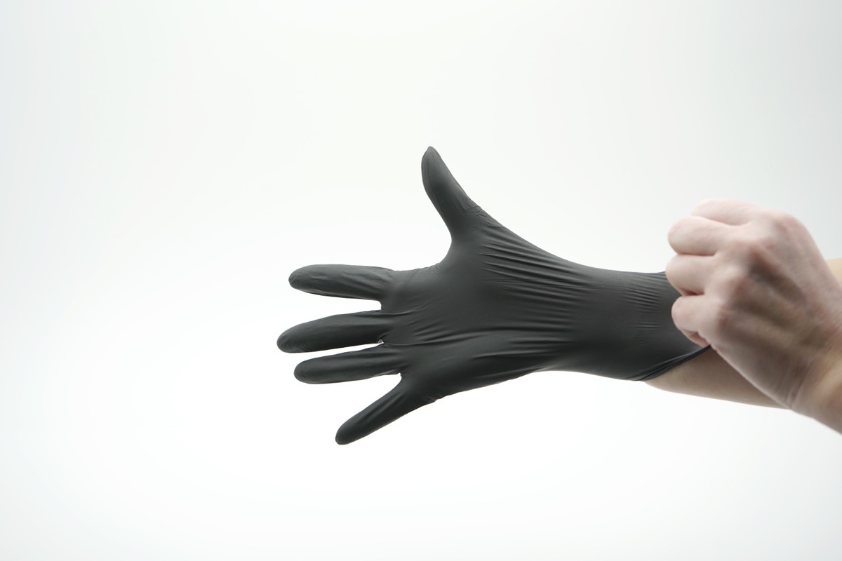 hand putting on dark gray or black nitrile glove